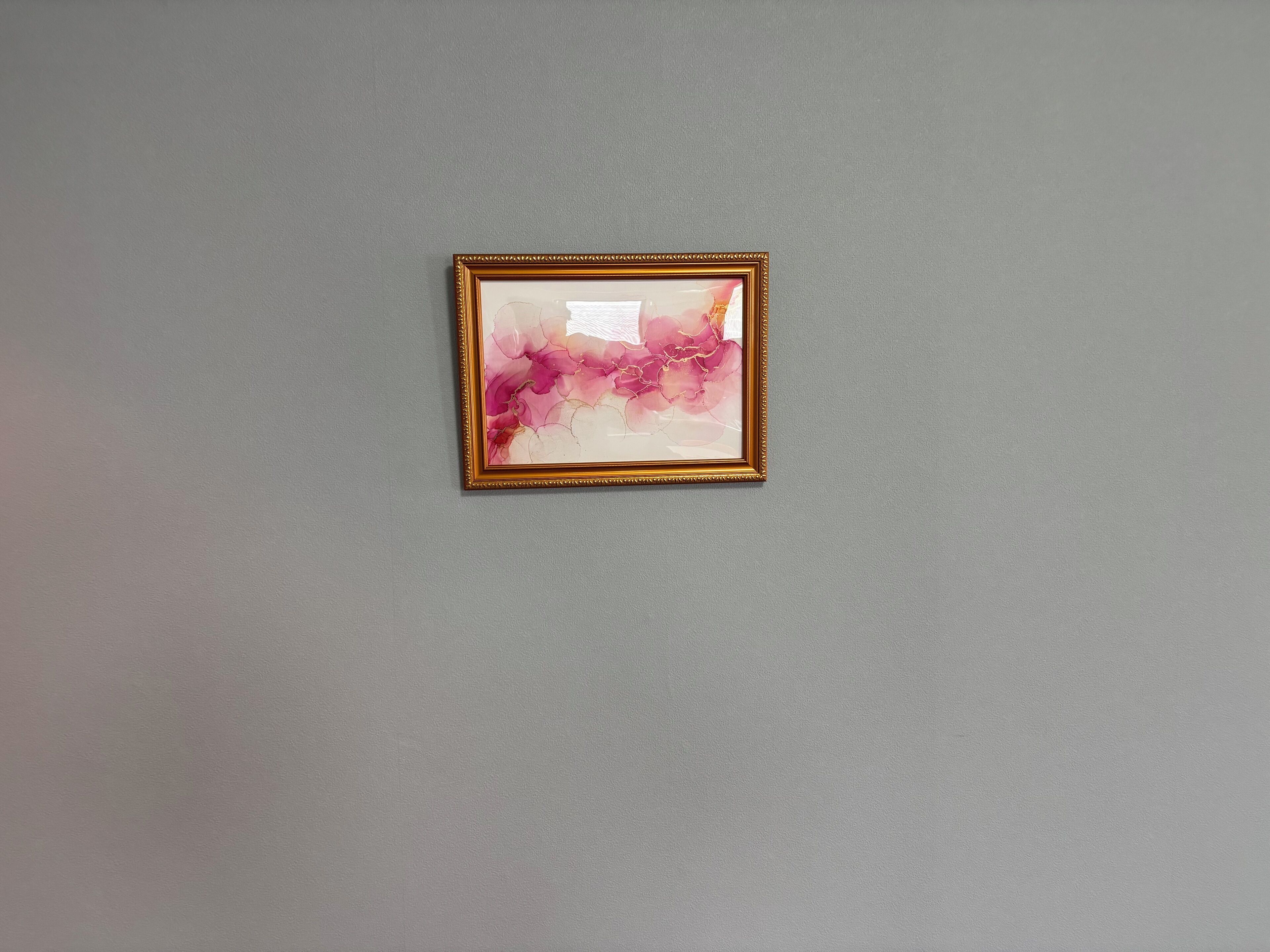 A framed abstract painting on a plain wall.