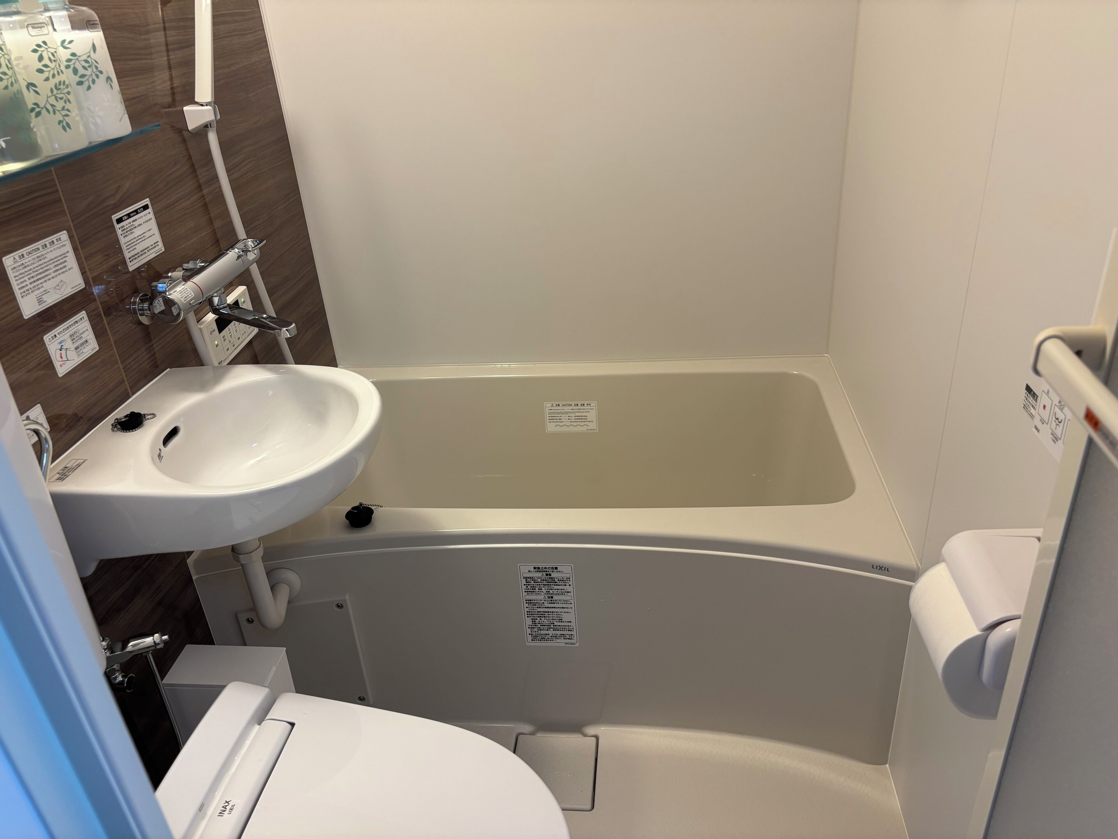 A bathroom with a white sink, a bathtub, and a toilet. There are signs on the walls and a shower curtain.