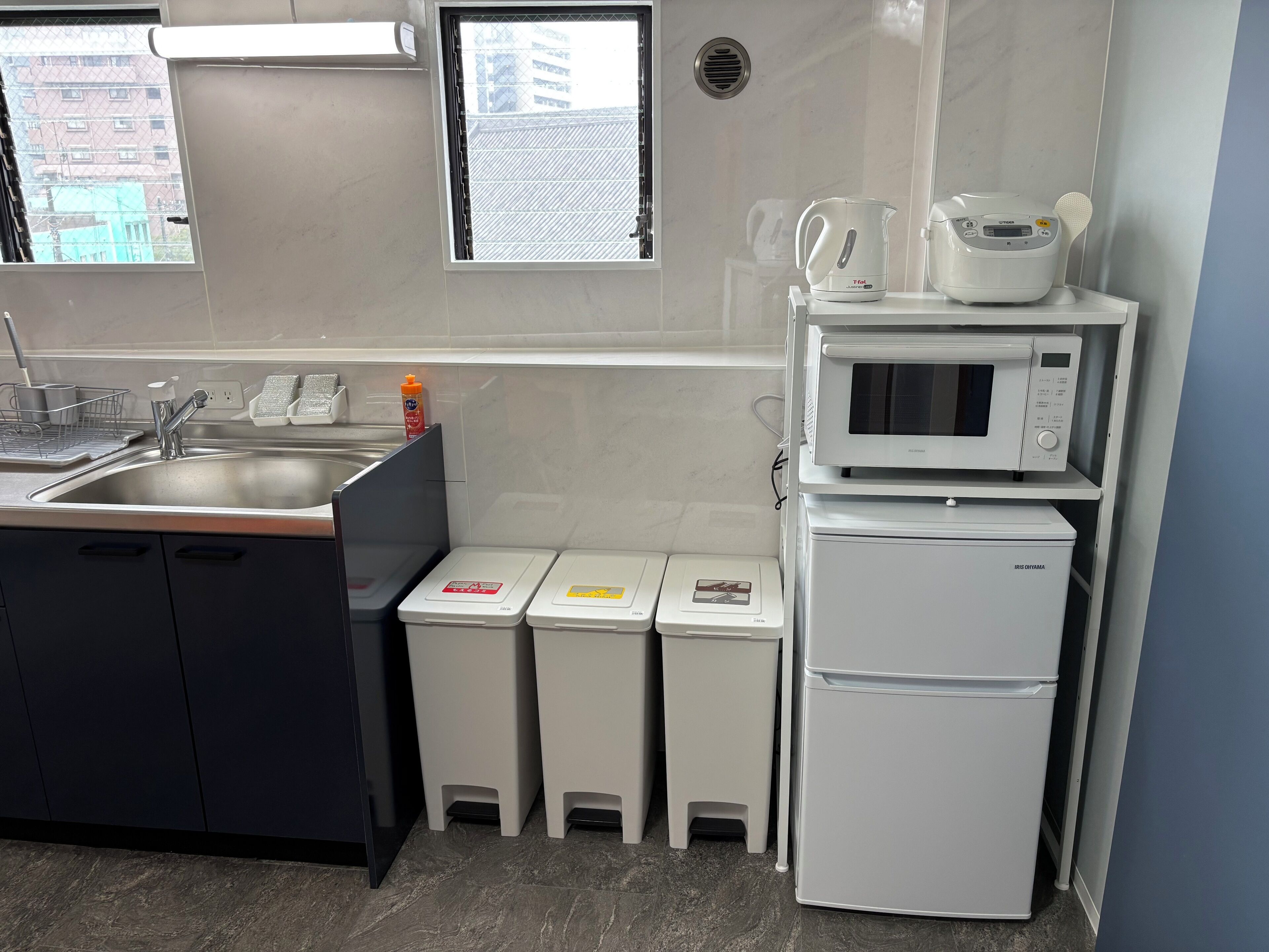 Una cocina moderna con un lavamanos de acero inoxidable, un microondas y un refrigerador.
