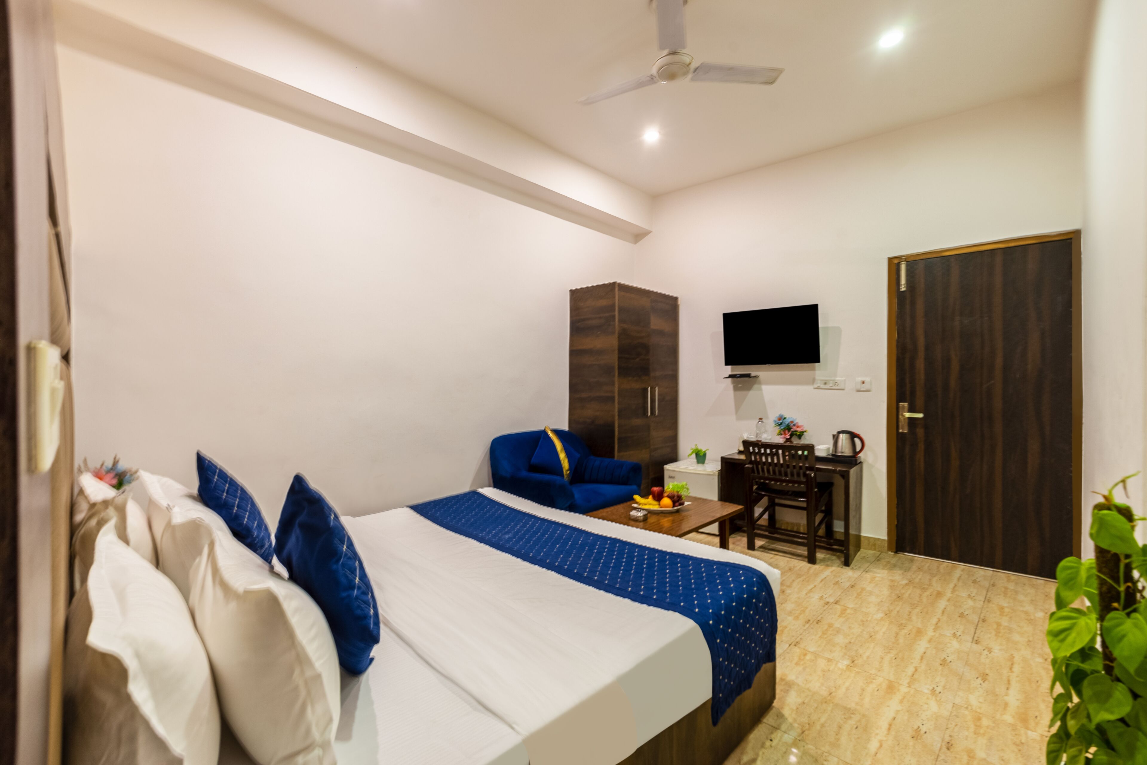 A hotel room with a bed, a desk, a chair, a wardrobe, a television, and a door.