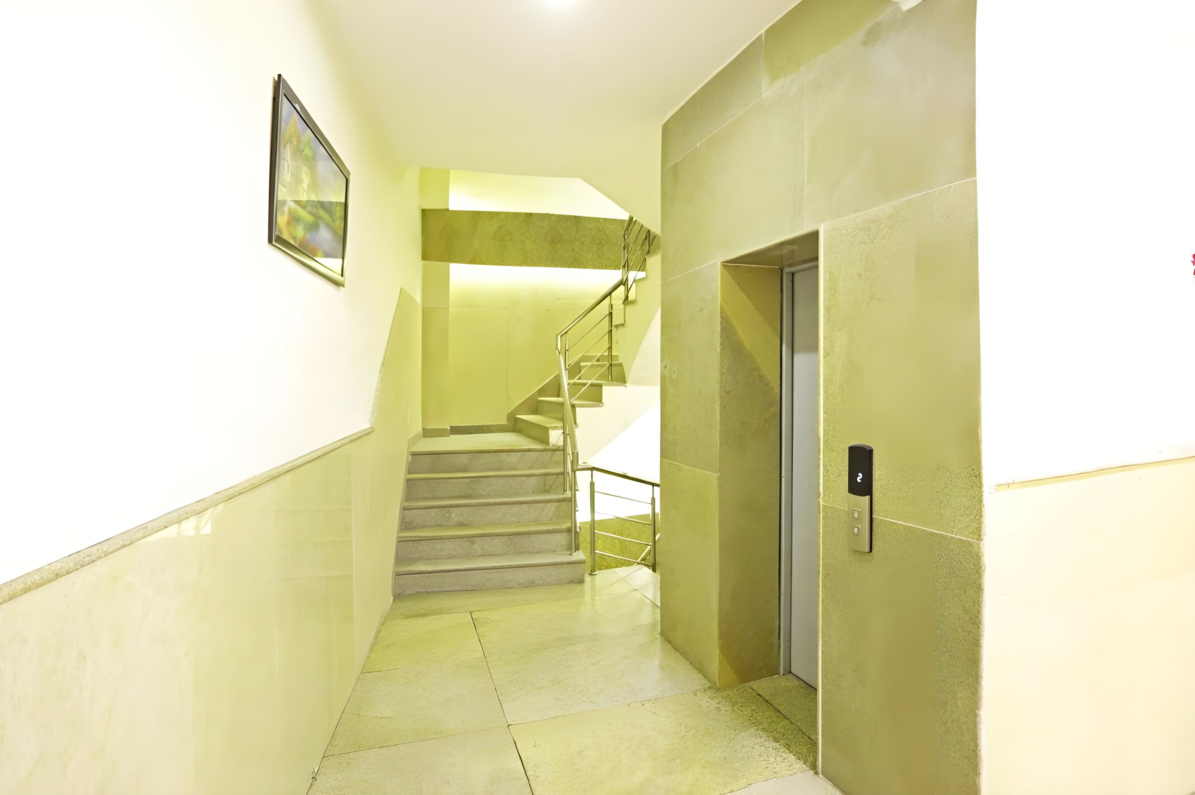A modern interior with a staircase, a door with a keypad, and a framed picture on the wall.