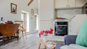 Een moderne keuken met witte kasten, een inbouwoven en een marmeren aanrechtblad.