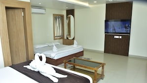 A hotel room with a bed, a wooden bedside table, a TV, and a mirror. -  Safal Exotica Very Close to Sea Beach (Puri)