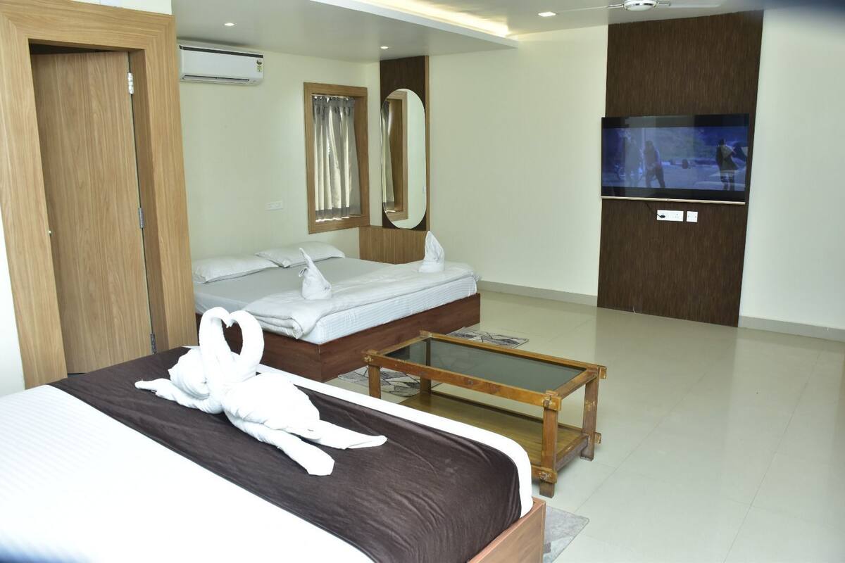 A hotel room with a bed, a wooden bedside table, a TV, and a mirror.