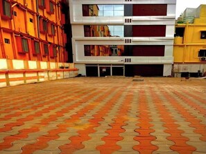 A courtyard with a patterned floor and a building with multiple floors and balconies. -  Safal Exotica Very Close to Sea Beach (Puri)