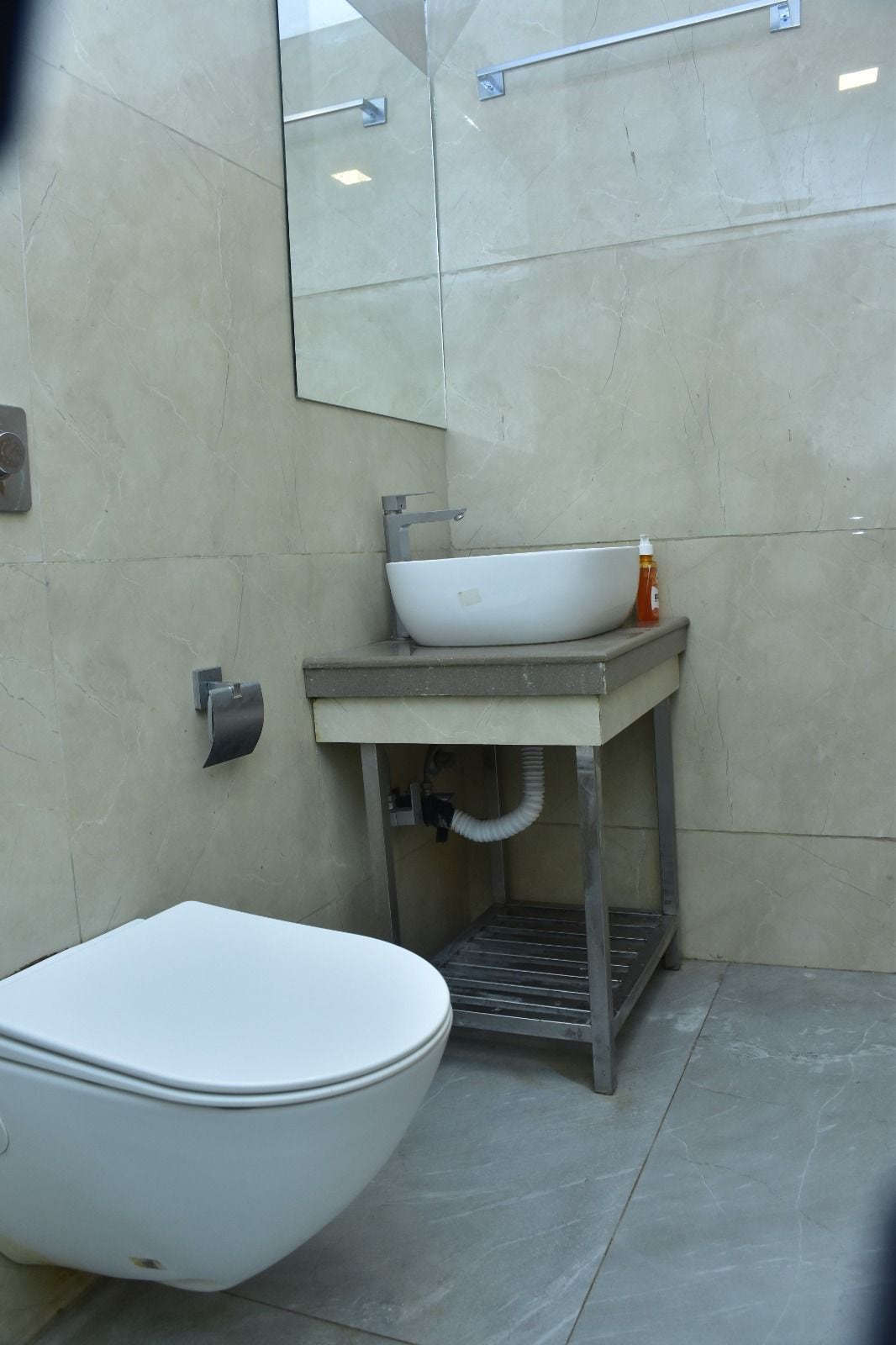 A modern bathroom with a white toilet, a vessel sink, and a mirror above the sink.