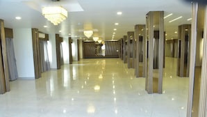 A spacious, well-lit hallway with reflective marble floors and modern chandeliers. -  Safal Exotica Very Close to Sea Beach (Puri)