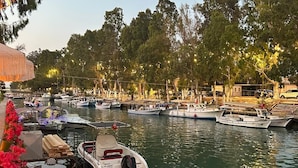 A waterfront restaurant with outdoor seating overlooking a marina with several boats. - Casa Kawa (Arsuz)