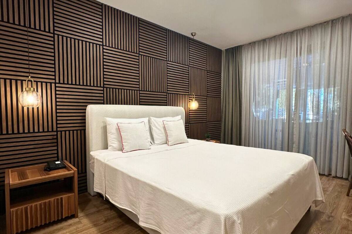Ein modernes Hotelzimmer mit einem großen Bett, einer Wandpaneele aus Holz und einem Nachttisch.
