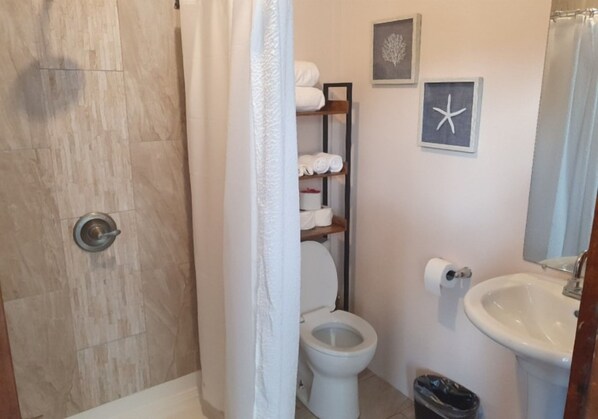 A bathroom with a shower, toilet, and sink.