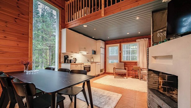 Eine moderne Hütte mit Essbereich, Küche und Kamin.