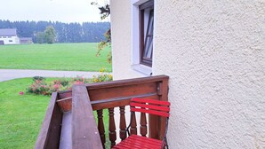 A wooden bench and a small red table with a vase of flowers on a balcony. - Wonderful private villa for 6 guests with WIFI and panoramic view (Wienern)
