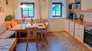A cozy kitchen with a dining area, featuring a wooden table, chairs, and a bench. There is a window with curtains, a clock on the wall, and a cross decoration. - Wonderful private villa for 6 guests with WIFI and panoramic view (Wienern)