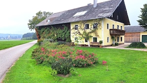 A two-story house with a sloped roof, a balcony, and a garden with pink flowers. - Wonderful private villa for 6 guests with WIFI and panoramic view (Wienern)