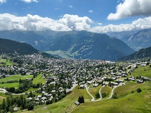 Eine Stadt in den Bergen, mit Häusern, die sich über das Tal verteilen, umgeben von üppiger Vegetation und Bergen.