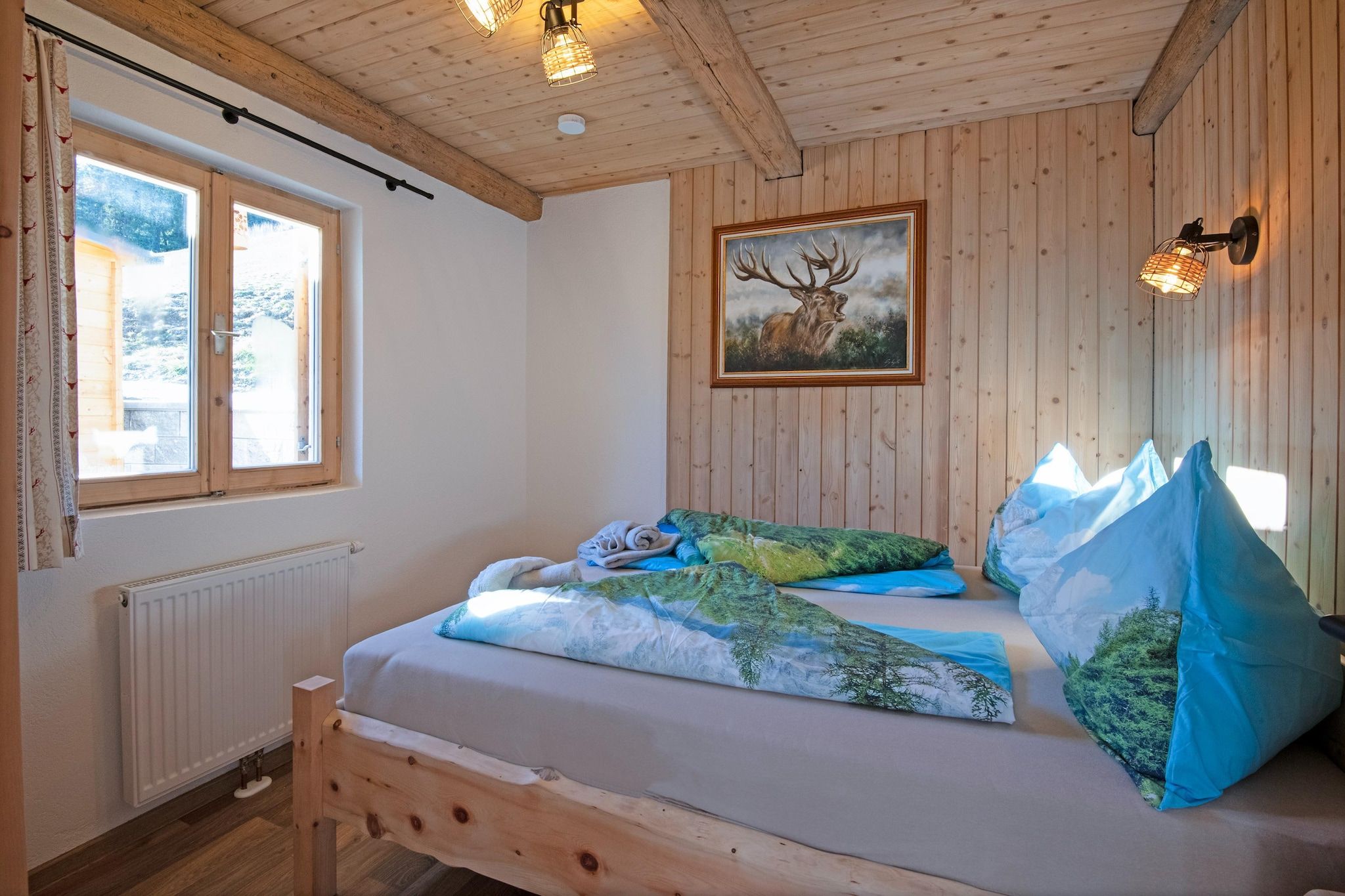 Una habitación con una cama de madera, una ventana, un radiador y un cuadro de un ciervo.