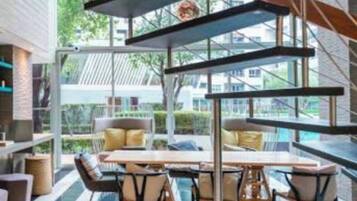 A modern interior with a glass wall, a dining area with a table and chairs, and shelves with decorative items.