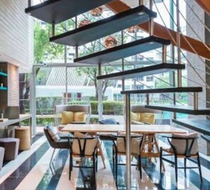 Een modern interieur met een eethoek, planken met flessen en uitzicht door grote ramen.