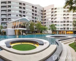 Een modern hotel met een zwembadgedeelte, inclusief een opvallend gebouw met een gebogen dak en een ronde waterpartij.