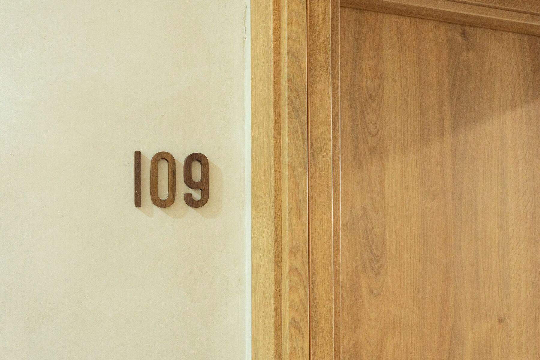 Une porte en bois portant le numéro 109, sur un mur de couleur beige.