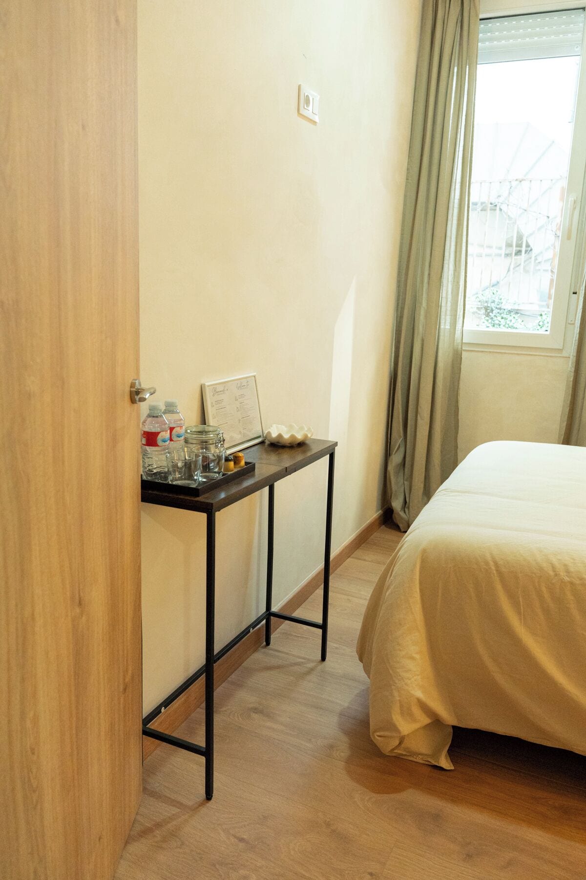 Een slaapkamer met een bed, een nachtkastje met een lijst en een raam met gordijnen.