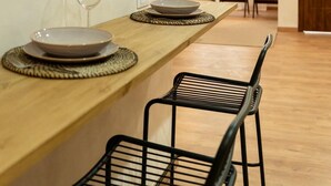 Un coin repas avec une table en bois, deux chaises noires et un verre de vin.