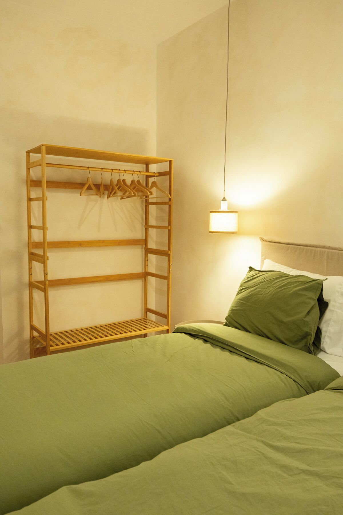 Une pièce comprenant un lit, une armoire en bois et un luminaire suspendu.