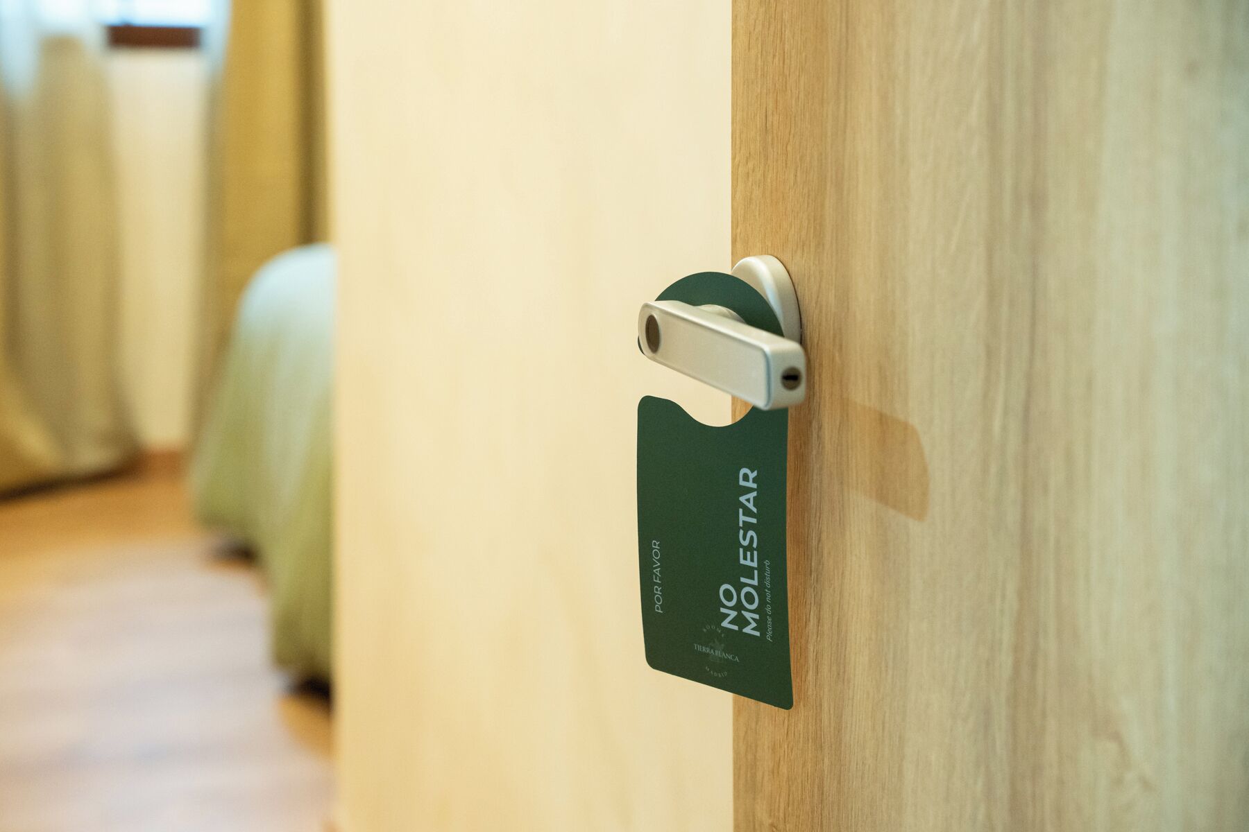A hotel room door with a sign that reads "NO MOLESTAR" and "POR FAVOR" indicating a request for no disturbances.