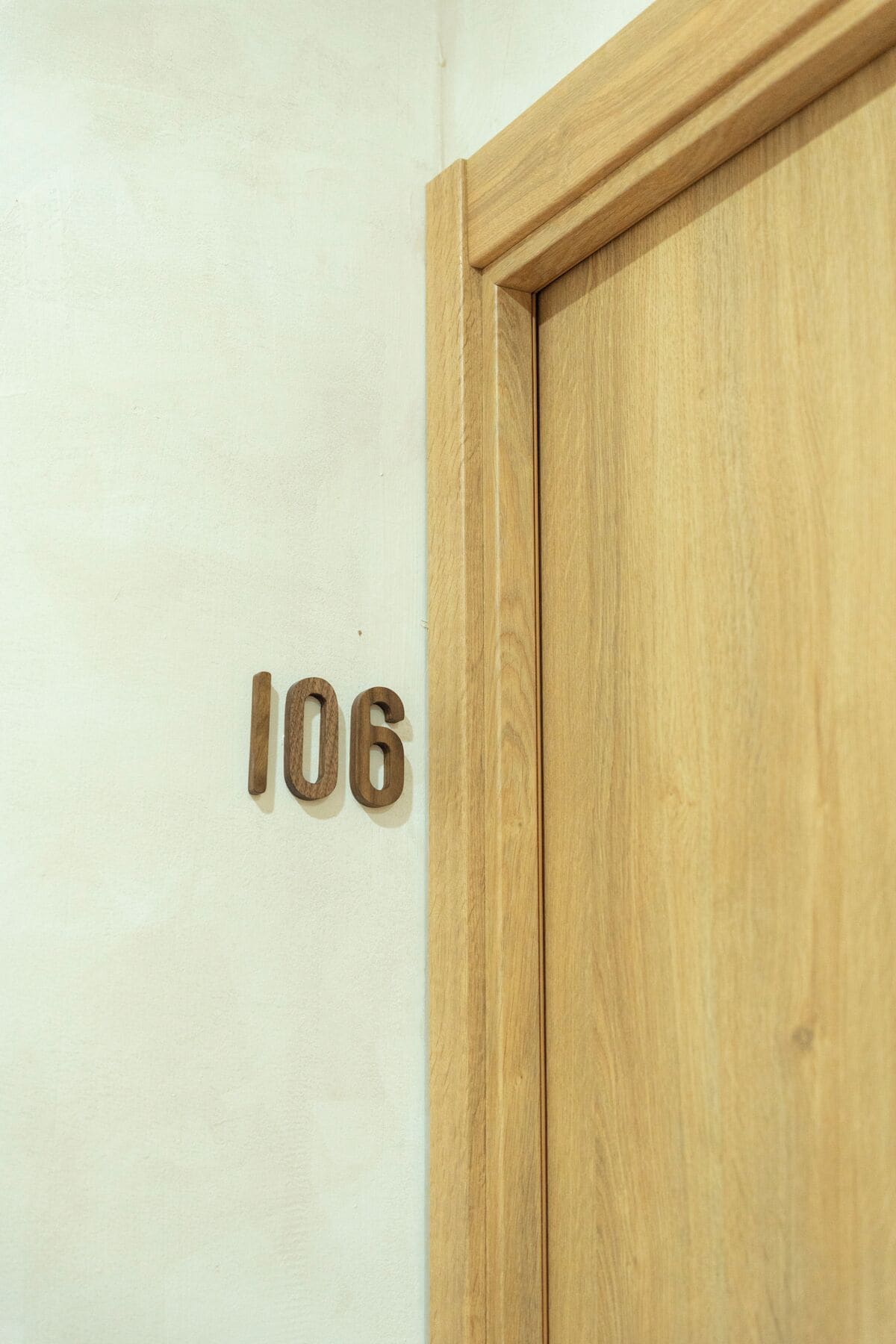 A wooden door with the number 106 on a white wall.