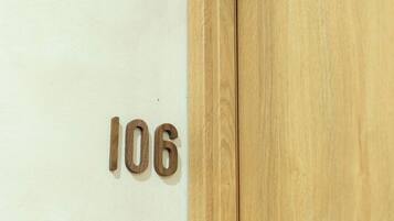 A wooden door with the number 106 on a white wall.