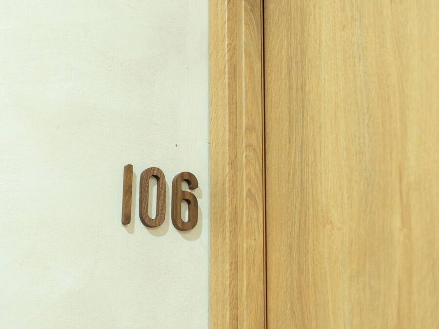 A wooden door with the number 106 on a white wall.