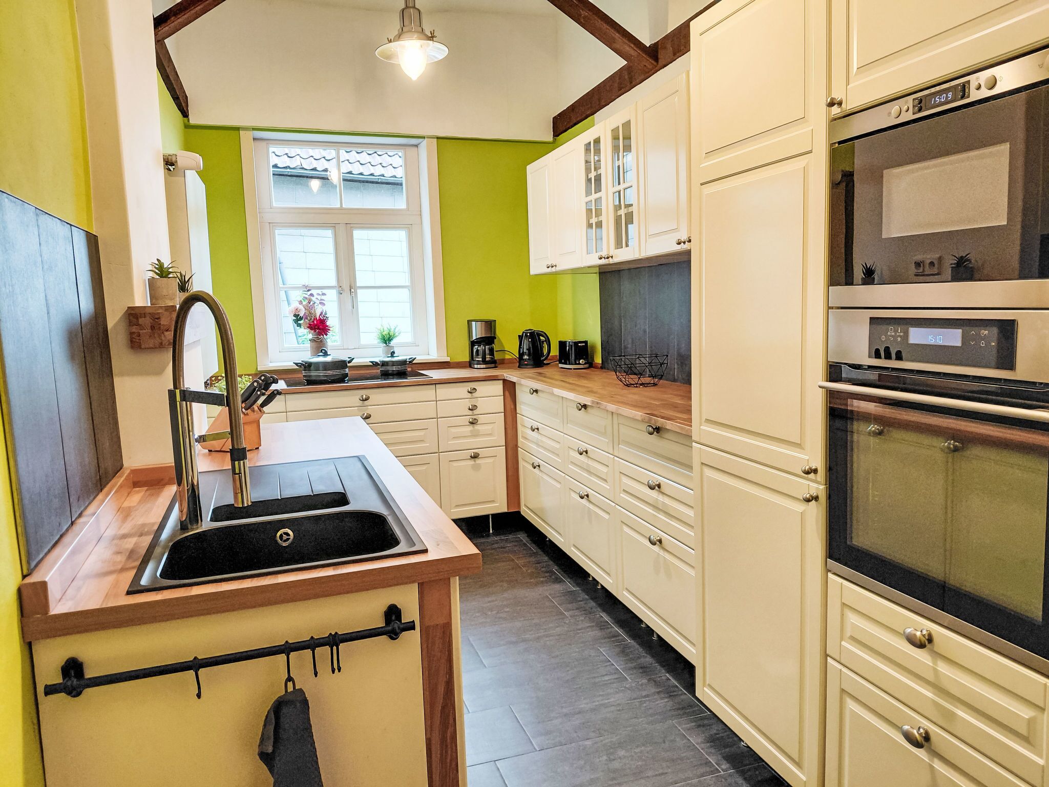 A kitchen with a sink, stove, oven, and cabinets.