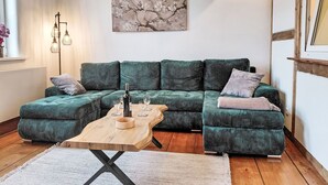 Una sala de estar moderna con un sofá seccional verde, una mesa de centro de madera y una obra de arte enmarcada en la pared.