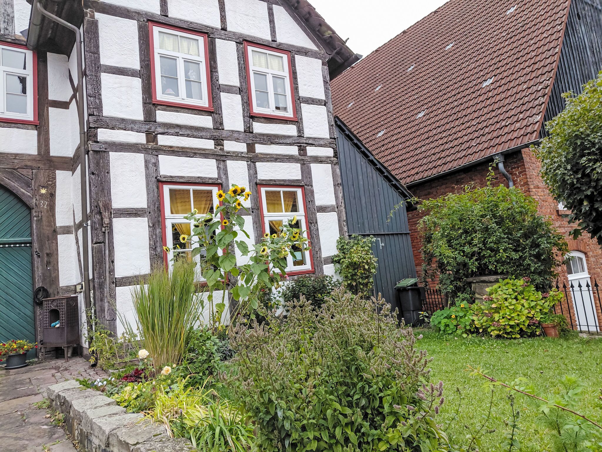 Une maison traditionnelle à colombages avec un jardin à l’avant.