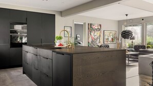 Uma cozinha moderna com armários escuros, uma ilha central e micro-ondas embutido.