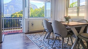 A dining area with a table, chairs, and a view of mountains through large windows.