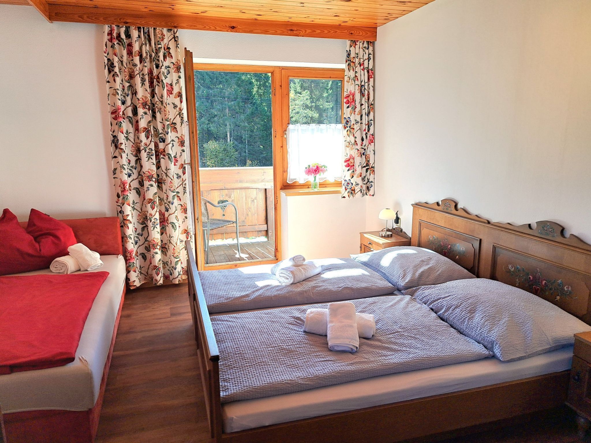 Een slaapkamer met een houten bed, een rode bank en een balkon met houten leuning.