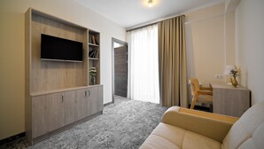 Un soggiorno moderno con una televisione a schermo piatto, un divano, un mobiletto in legno e un tavolino con un vaso.