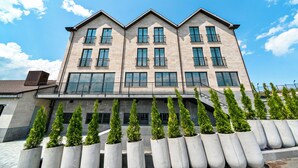 Un edificio moderno con facciata simmetrica, numerosi balconi e una serie di fioriere con piante sul davanti.