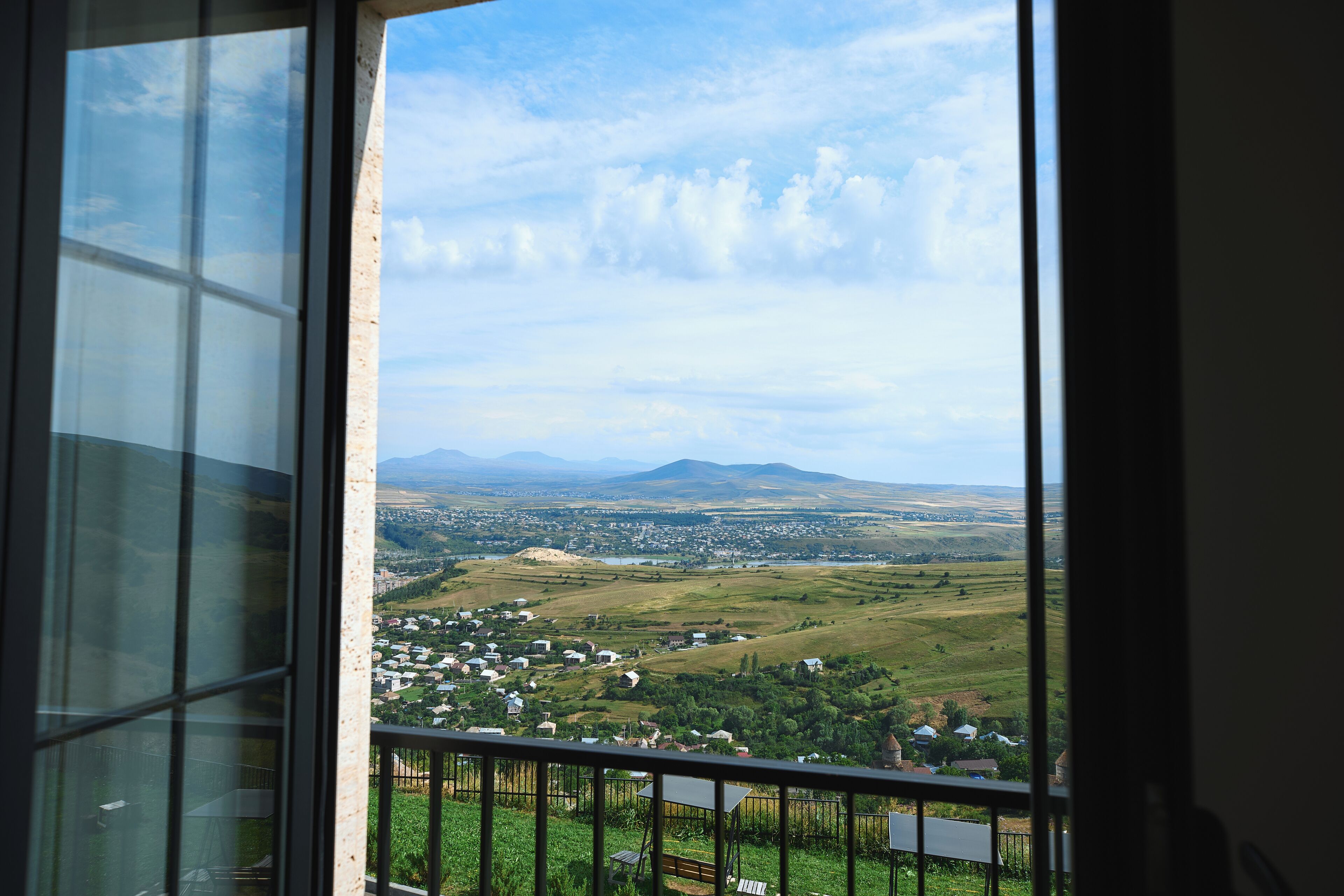 Blick aus einem Fenster auf eine Stadt mit Häusern und einem entfernten Gebirgszug.