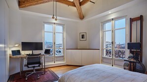 A bedroom with a bed, two desks with computers, a chair, and large windows with a city view. - Sublime apartment Center of Paris le Marais (Paris)