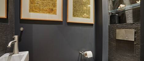 A modern bathroom with a sink, toilet, and framed artwork on the wall.
