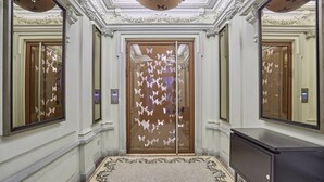 A hallway with ornate wall moldings, a patterned floor, and a door with butterfly decals. - Sublime apartment Center of Paris le Marais (Paris)