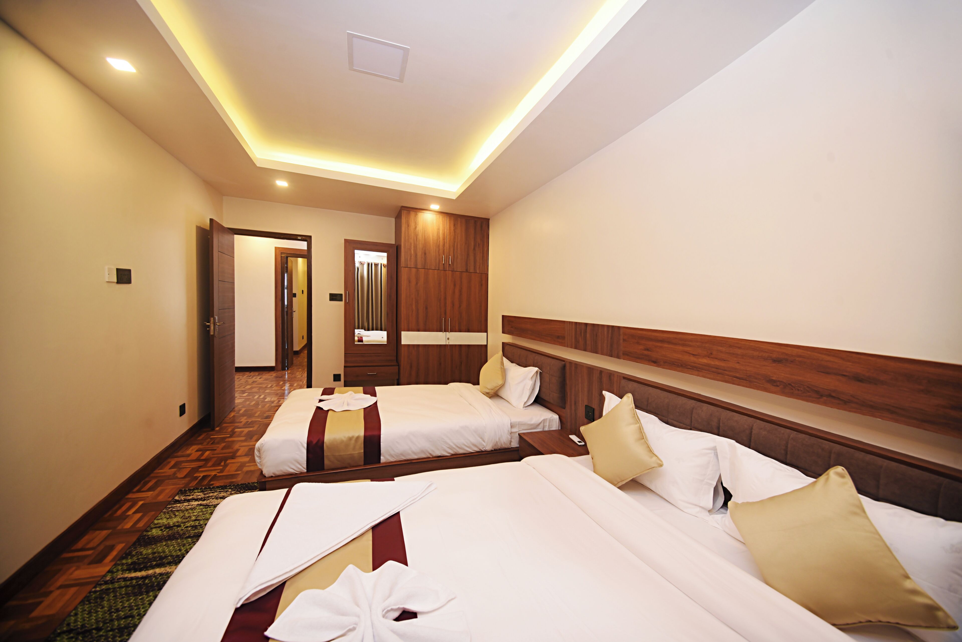 A hotel room with two beds, wooden headboards, and a carpeted floor.