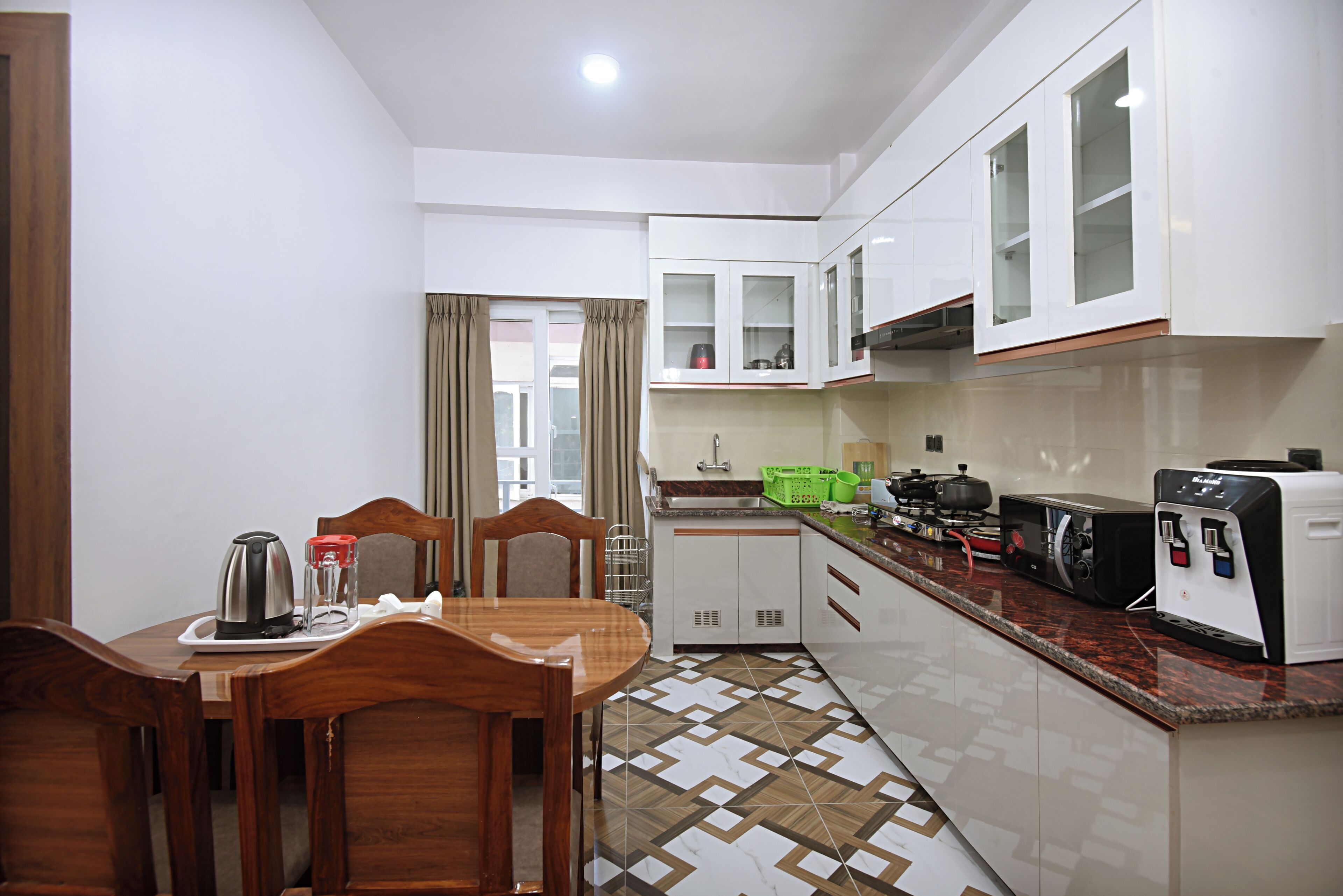 A compact kitchen with white cabinets, a dining table with chairs, and a coffee maker.