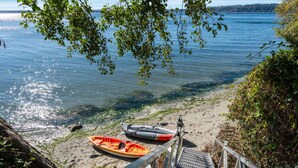 A kayak and a canoe on a sandy beach with a metal staircase leading down to the water. - The Shoreside Serenity Retreat at Indianola Beach (Indianola)