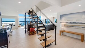 A modern interior with a spiral staircase, a dining area with a view, and a large painting on the wall. - The Shoreside Serenity Retreat at Indianola Beach (Indianola)