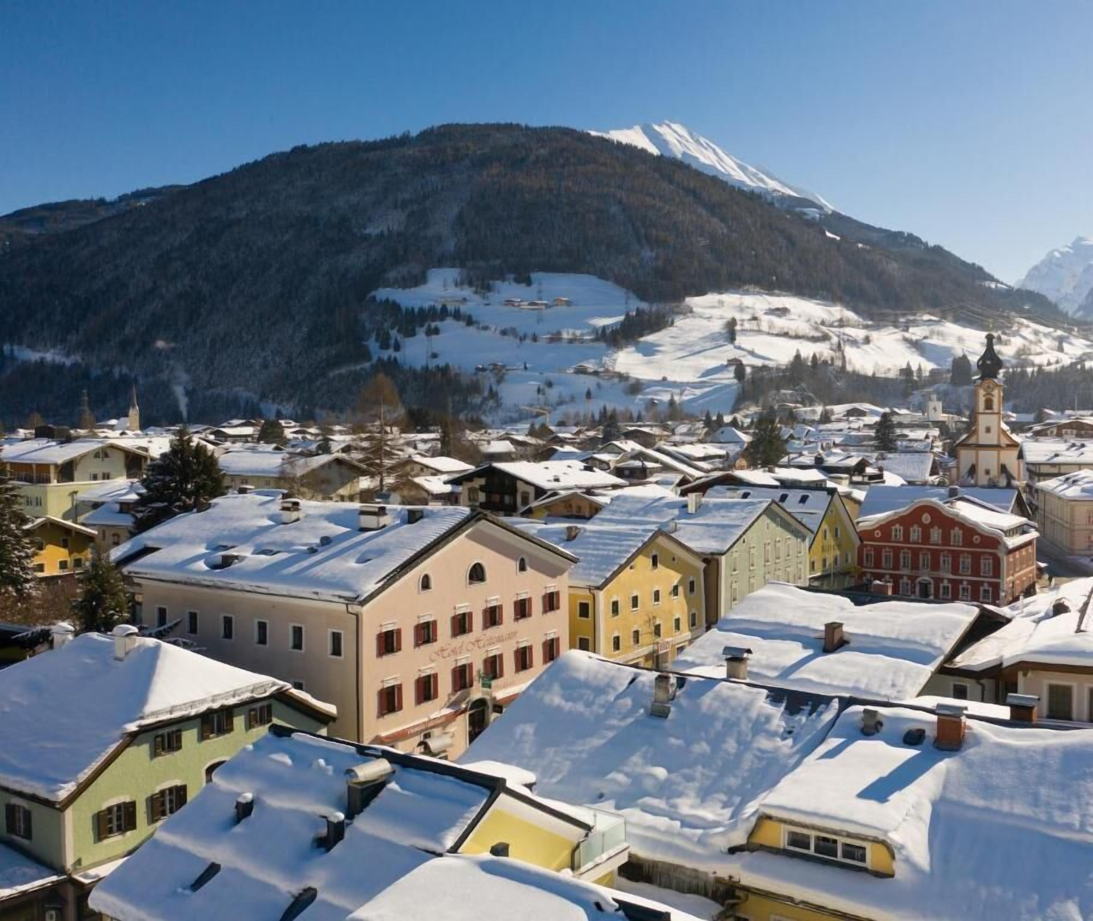 Un pueblo cubierto de nieve con edificios tradicionales y una montaña al fondo.