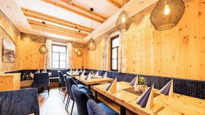 Un restaurant aux murs et au plafond en bois, avec des banquettes rembourrées en tissu bleu et des tables en bois, sur lesquelles sont posées des serviettes.