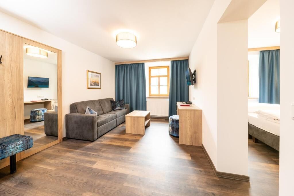 A compact living space with a sofa, a small coffee table, a wooden cabinet, and a bed.